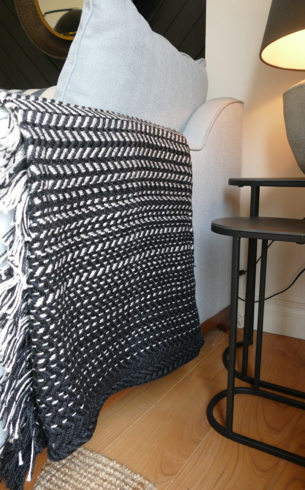 woven black and white blanket on arm of couch